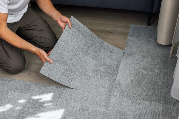 Person installing gray carpet tiles on a wooden floor, enhancing the space’s aesthetics. If you're considering an upgrade, epoxy floor coatings provide additional durability and shine, ensuring a lasting finish for high-traffic areas. Person installing gray carpet tiles on a wooden floor, enhancing the space’s aesthetics. If you're considering an upgrade, epoxy floor coatings provide additional durability and shine, ensuring a lasting finish for high-traffic areas.